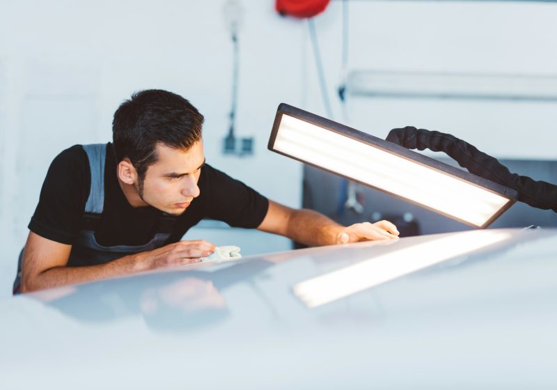 Car mechanic working to remove dent in workshop.