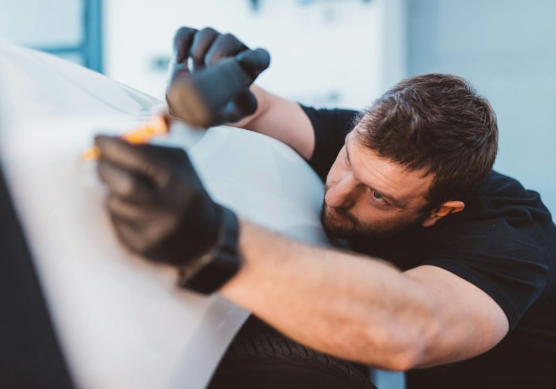 Car mechanic working to remove dent in workshop.