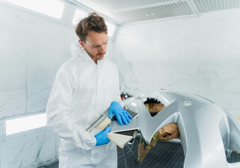 Young male car body repair worker in vehicle painting booth