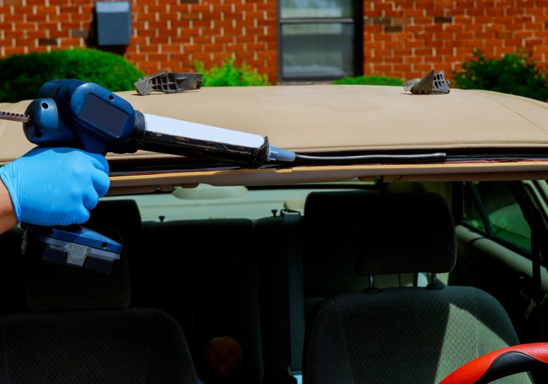 Automobile windshield replacement man using silicone tools to fix special workers replacing